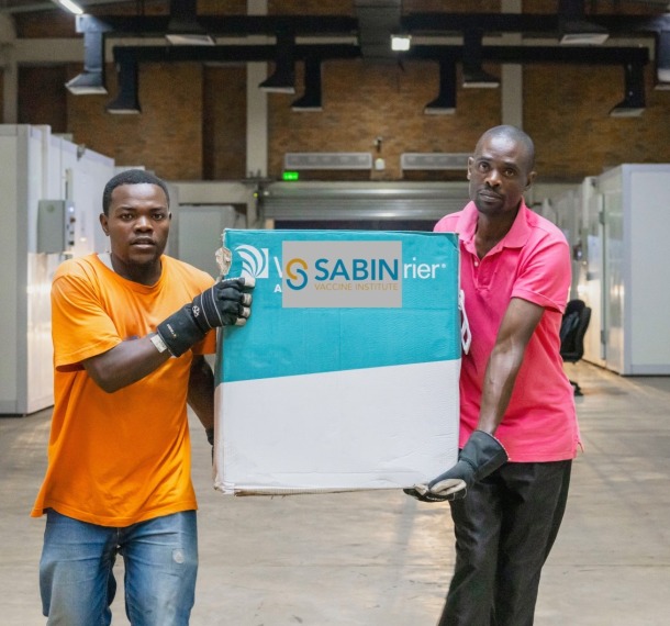 Two men carry a box of Sabin Marburg vaccines