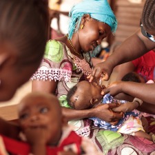 BOOST-Mother-holding-child-receiving-oral-polio-vaccine