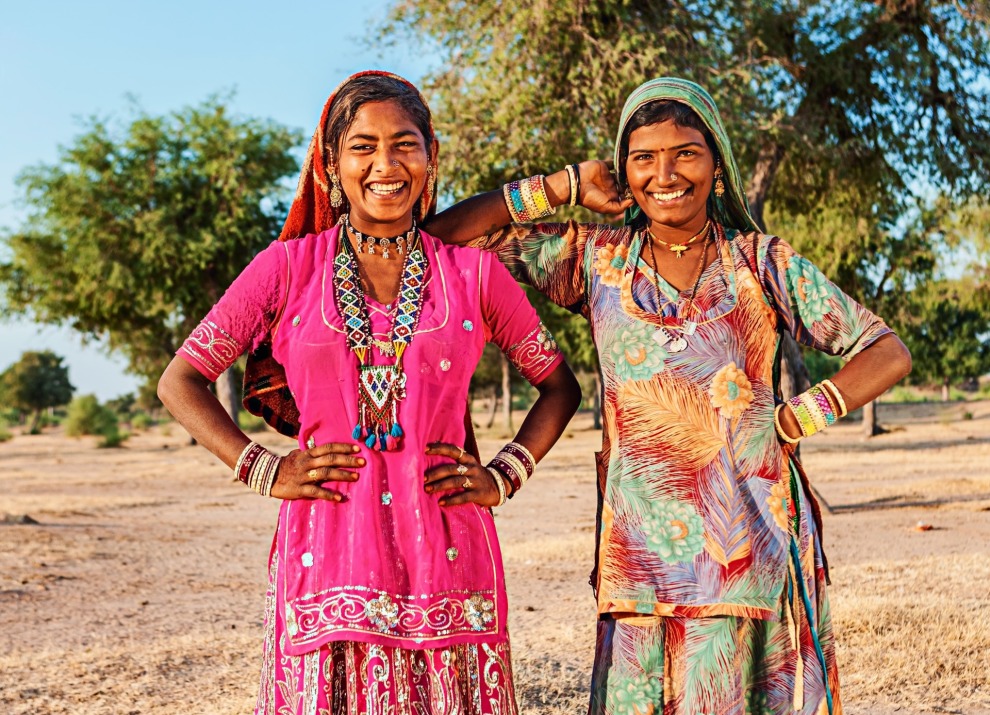 Two Indian women smiling at the camera with colorful dresses