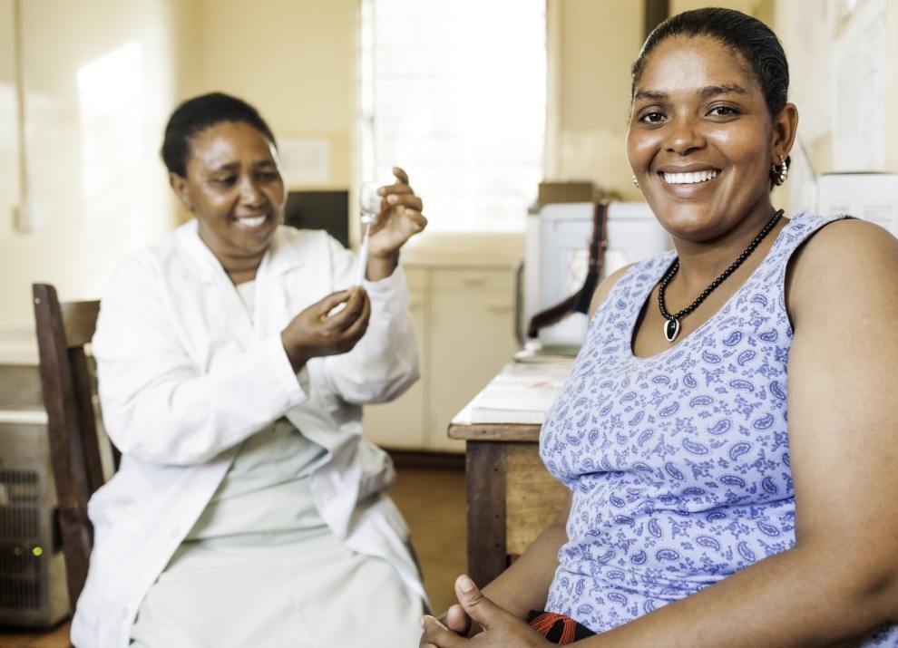 A doctor preparing a vaccine while the patient smiles at the camera